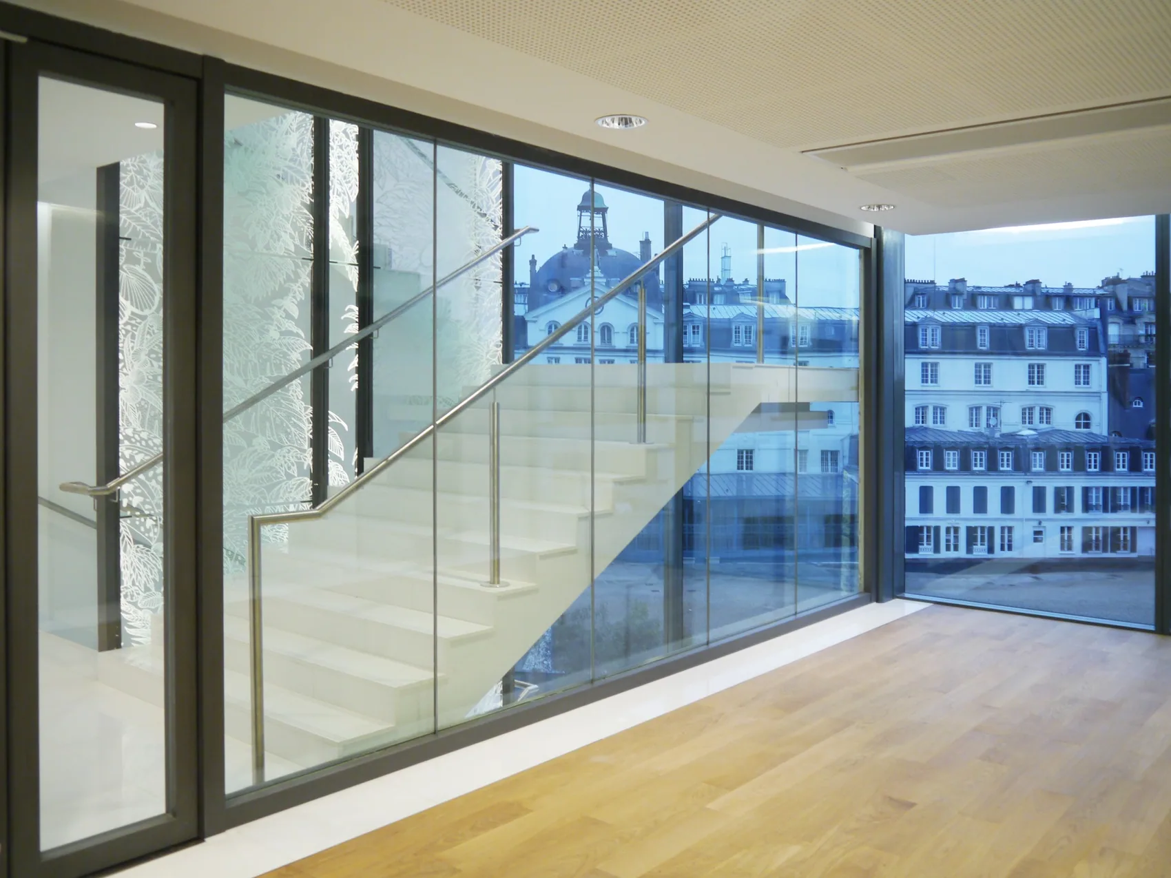 Escalier contemporain derrière une paroi vitrée, espace tertiaire
